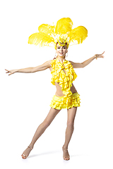 Image showing Beautiful young woman in carnival, stylish masquerade costume with feathers dancing on white studio background.