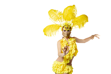 Image showing Beautiful young woman in carnival, stylish masquerade costume with feathers dancing on white studio background.