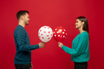 Image showing Beautiful couple in love on red studio background. Valentine\'s Day, love and emotions concept