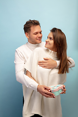 Image showing Beautiful couple in love on blue studio background. Valentine\'s Day, love and emotions concept