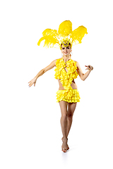 Image showing Beautiful young woman in carnival, stylish masquerade costume with feathers dancing on white studio background.