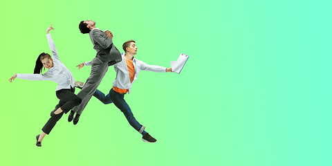 Image showing Happy office workers jumping and dancing in casual clothes or suit on gradient neon fluid background. Flyer with copyspace