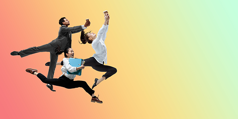 Image showing Happy office workers jumping and dancing in casual clothes or suit on gradient neon fluid background. Flyer with copyspace