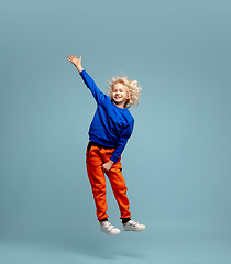 Image showing Happy curly boy isolated on blue studio background. Looks happy, cheerful, sincere. Copyspace. Childhood, education, emotions concept