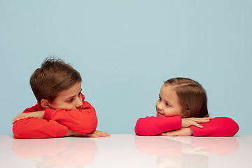 Image showing Happy children isolated on blue studio background. Look happy, cheerful, sincere. Copyspace. Childhood, education, emotions concept