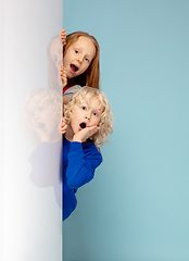 Image showing Happy children isolated on blue studio background. Look happy, cheerful, sincere. Copyspace. Childhood, education, emotions concept