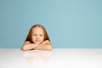 Image showing Happy redhair girl isolated on blue studio background. Looks happy, cheerful, sincere. Copyspace. Childhood, education, emotions concept