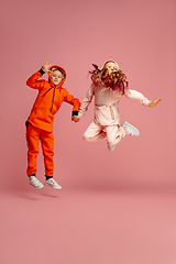 Image showing Happy children isolated on coral pink studio background. Look happy, cheerful, sincere. Copyspace. Childhood, education, emotions concept