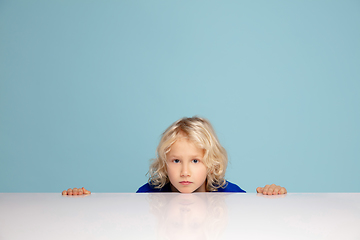 Image showing Happy curly boy isolated on blue studio background. Looks happy, cheerful, sincere. Copyspace. Childhood, education, emotions concept