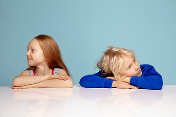 Image showing Happy children isolated on blue studio background. Look happy, cheerful, sincere. Copyspace. Childhood, education, emotions concept