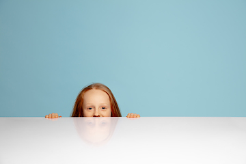 Image showing Happy redhair girl isolated on blue studio background. Looks happy, cheerful, sincere. Copyspace. Childhood, education, emotions concept