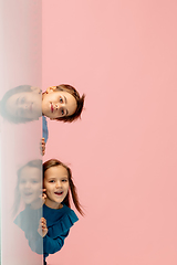 Image showing Happy children isolated on coral pink studio background. Look happy, cheerful, sincere. Copyspace. Childhood, education, emotions concept