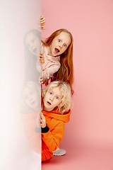 Image showing Happy children isolated on coral pink studio background. Look happy, cheerful, sincere. Copyspace. Childhood, education, emotions concept