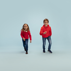 Image showing Happy children isolated on blue studio background. Look happy, cheerful, sincere. Copyspace. Childhood, education, emotions concept