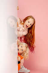 Image showing Happy children isolated on coral pink studio background. Look happy, cheerful, sincere. Copyspace. Childhood, education, emotions concept