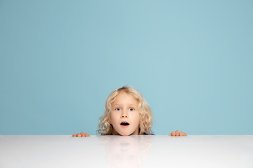 Image showing Happy curly boy isolated on blue studio background. Looks happy, cheerful, sincere. Copyspace. Childhood, education, emotions concept