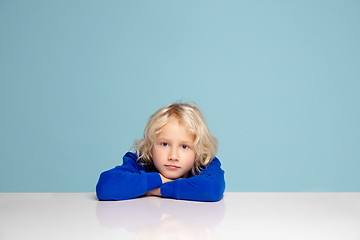 Image showing Happy curly boy isolated on blue studio background. Looks happy, cheerful, sincere. Copyspace. Childhood, education, emotions concept