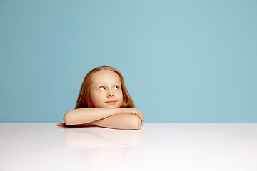 Image showing Happy redhair girl isolated on blue studio background. Looks happy, cheerful, sincere. Copyspace. Childhood, education, emotions concept