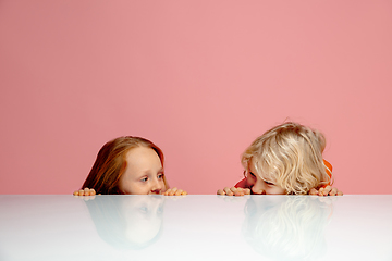 Image showing Happy children isolated on coral pink studio background. Look happy, cheerful, sincere. Copyspace. Childhood, education, emotions concept