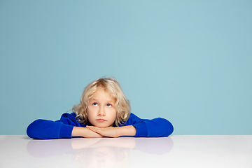 Image showing Happy curly boy isolated on blue studio background. Looks happy, cheerful, sincere. Copyspace. Childhood, education, emotions concept