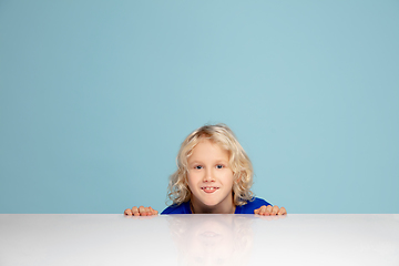 Image showing Happy curly boy isolated on blue studio background. Looks happy, cheerful, sincere. Copyspace. Childhood, education, emotions concept