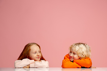 Image showing Happy children isolated on coral pink studio background. Look happy, cheerful, sincere. Copyspace. Childhood, education, emotions concept