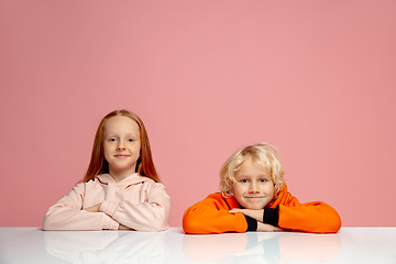 Image showing Happy children isolated on coral pink studio background. Look happy, cheerful, sincere. Copyspace. Childhood, education, emotions concept