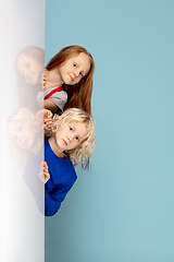 Image showing Happy children isolated on blue studio background. Look happy, cheerful, sincere. Copyspace. Childhood, education, emotions concept