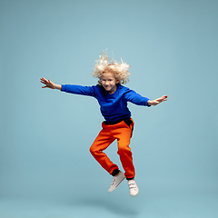 Image showing Happy curly boy isolated on blue studio background. Looks happy, cheerful, sincere. Copyspace. Childhood, education, emotions concept