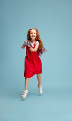 Image showing Happy redhair girl isolated on blue studio background. Looks happy, cheerful, sincere. Copyspace. Childhood, education, emotions concept