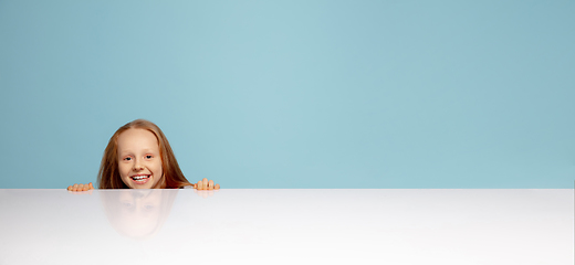 Image showing Happy redhair girl isolated on blue studio background. Looks happy, cheerful, sincere. Copyspace. Childhood, education, emotions concept