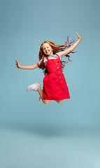 Image showing Happy redhair girl isolated on blue studio background. Looks happy, cheerful, sincere. Copyspace. Childhood, education, emotions concept