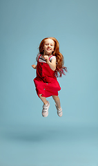 Image showing Happy redhair girl isolated on blue studio background. Looks happy, cheerful, sincere. Copyspace. Childhood, education, emotions concept