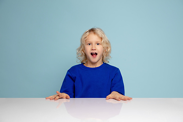 Image showing Happy curly boy isolated on blue studio background. Looks happy, cheerful, sincere. Copyspace. Childhood, education, emotions concept