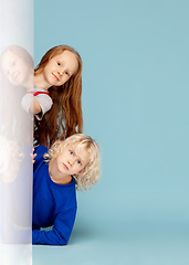 Image showing Happy children isolated on blue studio background. Look happy, cheerful, sincere. Copyspace. Childhood, education, emotions concept