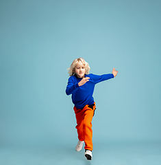 Image showing Happy curly boy isolated on blue studio background. Looks happy, cheerful, sincere. Copyspace. Childhood, education, emotions concept