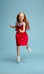 Image showing Happy redhair girl isolated on blue studio background. Looks happy, cheerful, sincere. Copyspace. Childhood, education, emotions concept