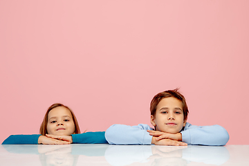 Image showing Happy children isolated on coral pink studio background. Look happy, cheerful, sincere. Copyspace. Childhood, education, emotions concept