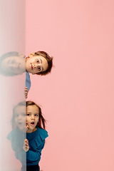 Image showing Happy children isolated on coral pink studio background. Look happy, cheerful, sincere. Copyspace. Childhood, education, emotions concept