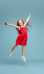 Image showing Happy redhair girl isolated on blue studio background. Looks happy, cheerful, sincere. Copyspace. Childhood, education, emotions concept