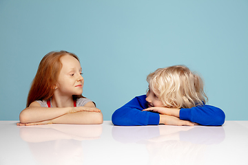 Image showing Happy children isolated on blue studio background. Look happy, cheerful, sincere. Copyspace. Childhood, education, emotions concept