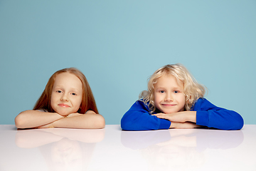 Image showing Happy children isolated on blue studio background. Look happy, cheerful, sincere. Copyspace. Childhood, education, emotions concept