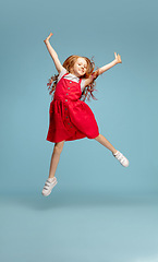 Image showing Happy redhair girl isolated on blue studio background. Looks happy, cheerful, sincere. Copyspace. Childhood, education, emotions concept