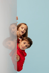 Image showing Happy children isolated on blue studio background. Look happy, cheerful, sincere. Copyspace. Childhood, education, emotions concept