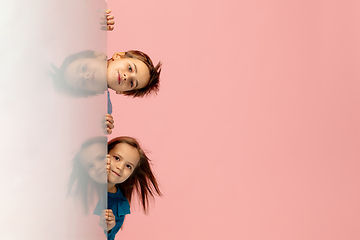 Image showing Happy children isolated on coral pink studio background. Look happy, cheerful, sincere. Copyspace. Childhood, education, emotions concept