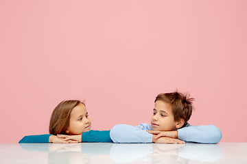 Image showing Happy children isolated on coral pink studio background. Look happy, cheerful, sincere. Copyspace. Childhood, education, emotions concept