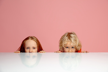 Image showing Happy children isolated on coral pink studio background. Look happy, cheerful, sincere. Copyspace. Childhood, education, emotions concept