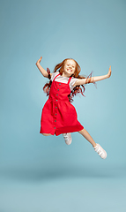 Image showing Happy redhair girl isolated on blue studio background. Looks happy, cheerful, sincere. Copyspace. Childhood, education, emotions concept