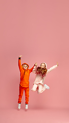 Image showing Happy children isolated on coral pink studio background. Look happy, cheerful, sincere. Copyspace. Childhood, education, emotions concept