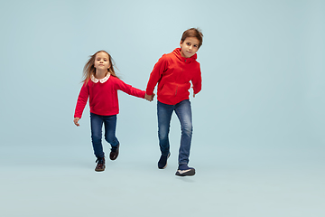 Image showing Happy children isolated on blue studio background. Look happy, cheerful, sincere. Copyspace. Childhood, education, emotions concept